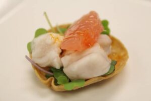 Red fish ceviche bite with grapefruit served in a mini tortilla shell