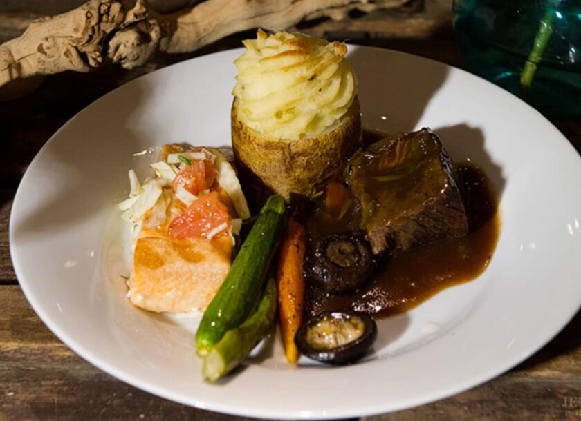 Braised beef short ribs with root vegetables, petite salmon filet plated entrees by crave catering